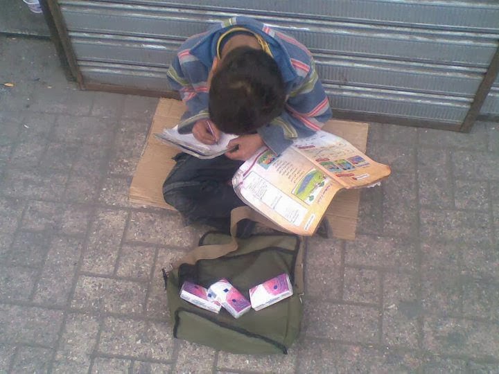 Μια εικόνα που σοκάρει - Παιδάκι πουλάει χαρτομάντιλα και διαβάζει τα μαθήματά του - Φωτογραφία 2