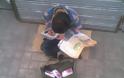 Μια εικόνα που σοκάρει - Παιδάκι πουλάει χαρτομάντιλα και διαβάζει τα μαθήματά του - Φωτογραφία 1