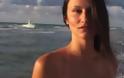 Μοντέλο γυρίζει βίντεο στην παραλία ενώ από πίσω περνούν μετανάστες